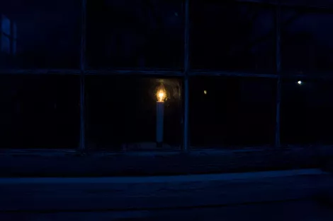A candle glowing behind a window A candle glowing behind a window